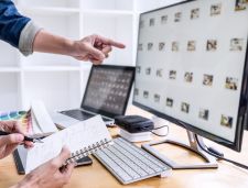hand pointing to stock images on computer screen